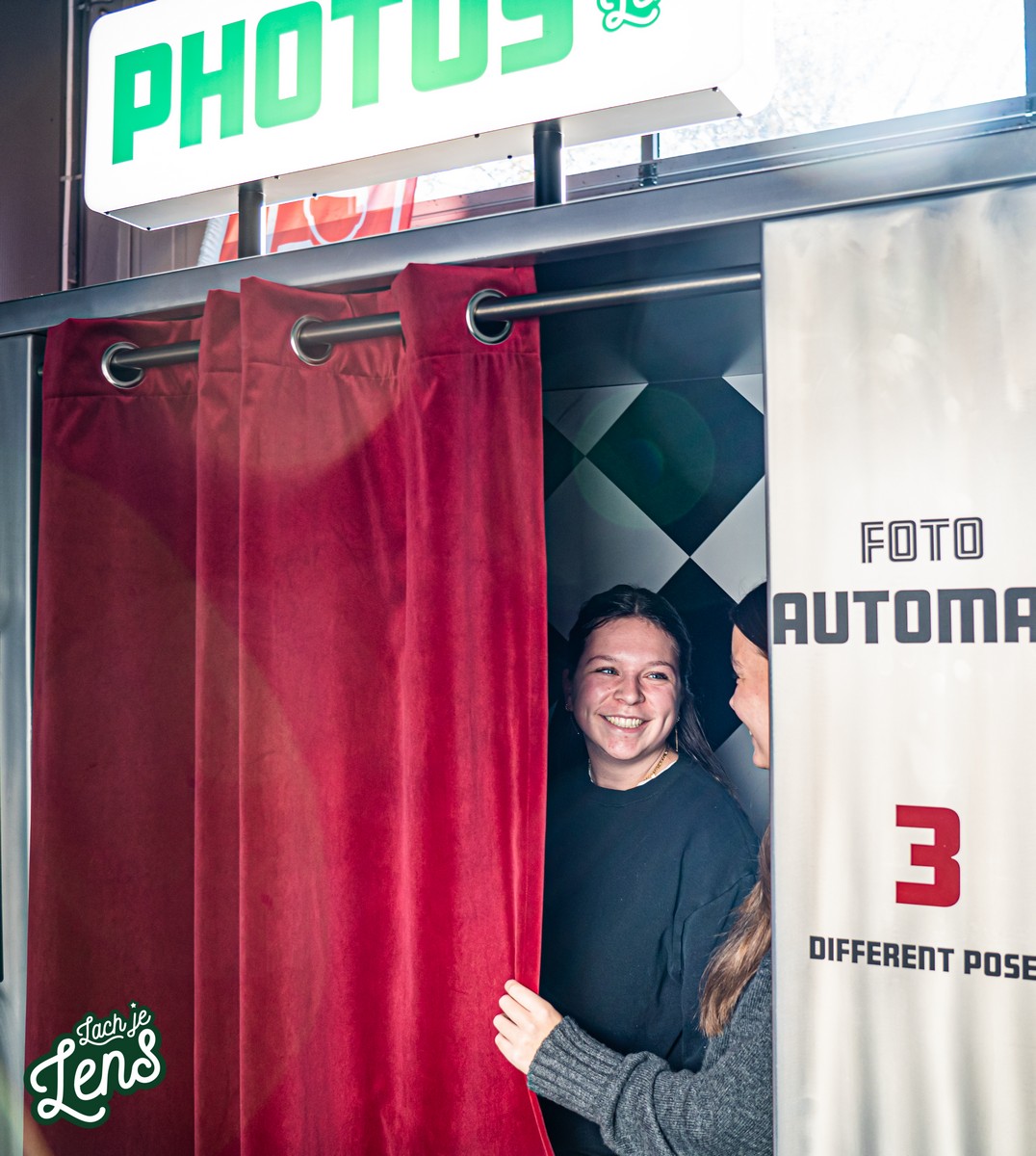 vrouw kijkt door het gordijn van een fotohokje